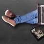 A man sat on the floor working from a laptop while it rests on his legs. 